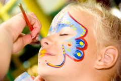 Beautiful girl with blue eyes with painted butterfly on her face